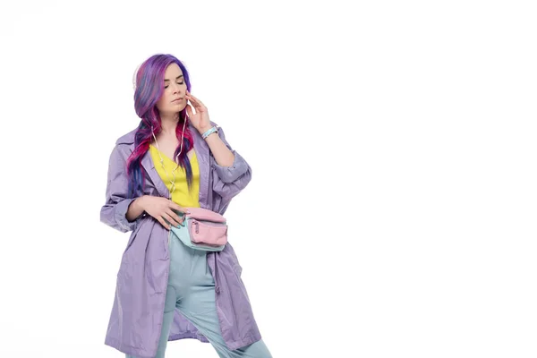 Belle jeune femme en trench coat violet écouter de la musique avec écouteurs isolés sur blanc — Photo de stock