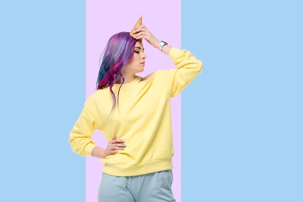 Young woman pretending unicorn with waffle cone on forehead on creative background — Stock Photo