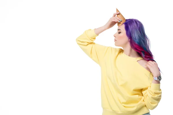 Mujer joven con estilo fingiendo unicornio con cono de gofre en la frente aislado en blanco - foto de stock