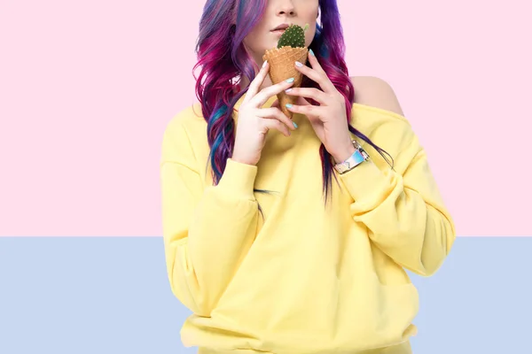 Cropped shot of woman holding cactus plant in ice cream waffle cone on creative background — Stock Photo