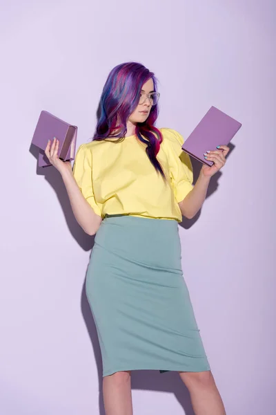 Attractive young woman with colorful hair holding books on pink — Stock Photo