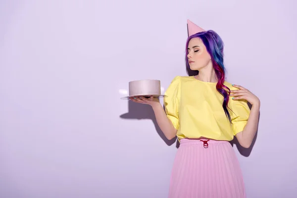 Belle jeune femme en chapeau de fête avec des cheveux colorés tenant gâteau d'anniversaire — Photo de stock