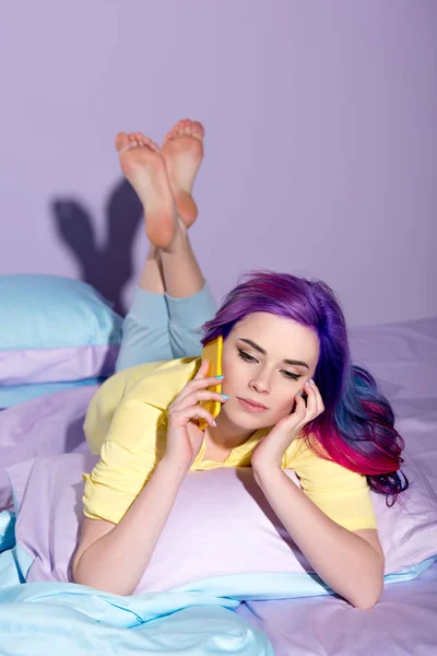 Beautiful young woman with colorful hair talking by phone in bed — Stock Photo