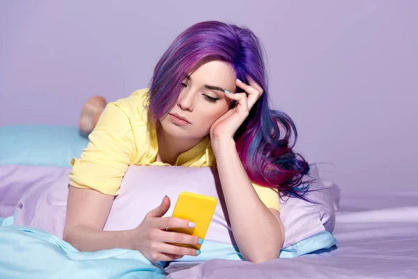 Annoiato giovane donna utilizzando smartphone a letto — Foto stock