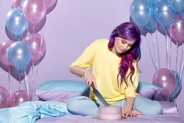 Bela jovem mulher corte bolo de aniversário na cama — Fotografia de Stock