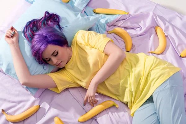 Visão de alto ângulo da jovem deitada na cama com bananas — Fotografia de Stock