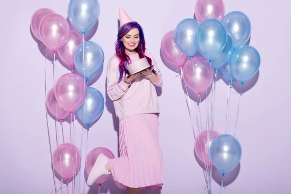 Schöne junge Frau mit Geburtstagstorte und Partyhut auf rosa — Stockfoto