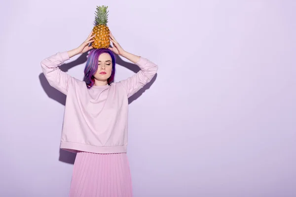 Attractive young woman in pink sweatshirt holding pineapple on head — Stock Photo