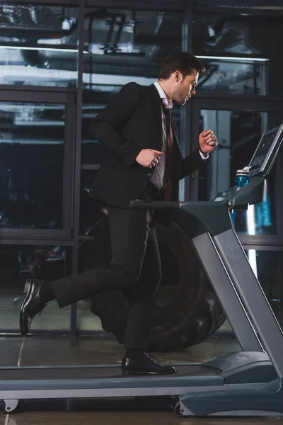 Bel homme d'affaires courir sur tapis roulant dans la salle de gym — Photo de stock