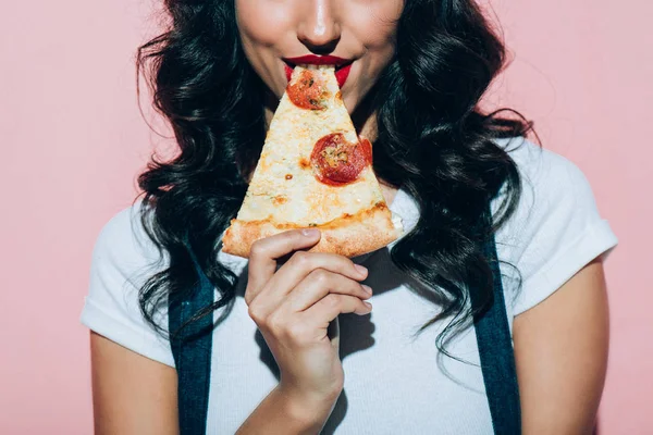 Обрізаний знімок жінки, що їсть піцу на рожевому фоні — стокове фото