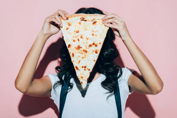 Obscured view of woman covering face with piece of pizza on pink background — Stock Photo