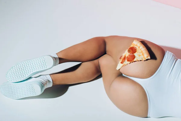 Parcial vista de pedazo de pizza en botín femenino - foto de stock