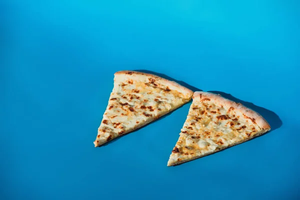 Крупным планом кусочки вареной пиццы, изолированные на голубом фоне — стоковое фото