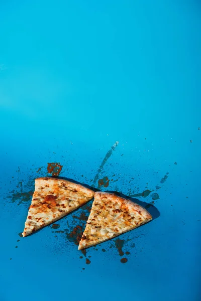 Close up view of pieces of cooked pizza on blue backdrop — Stock Photo