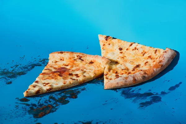 Vista de cerca de pedazos de pizza cocida sobre fondo azul - foto de stock