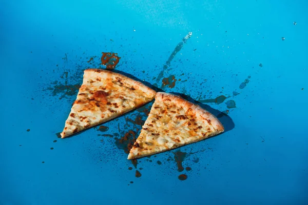 Vista de cerca de pedazos de pizza cocida sobre fondo azul - foto de stock