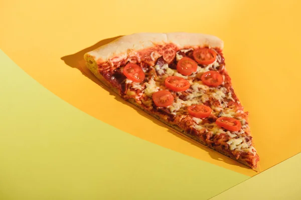 Close up view of piece of italian pizza with cherry tomatoes on colorful backdrop — Stock Photo