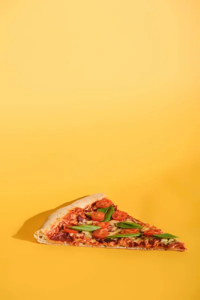 Vista de perto de pedaço de pizza com tomate cereja e manjericão em fundo laranja — Fotografia de Stock