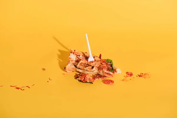 Close up view of disposable fork in smashed piece of pizza on orange backdrop — Stock Photo