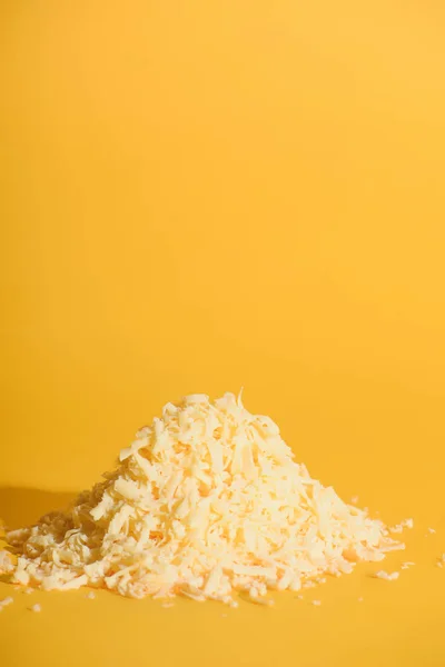 Vue rapprochée du fromage râpé sur fond orange — Photo de stock