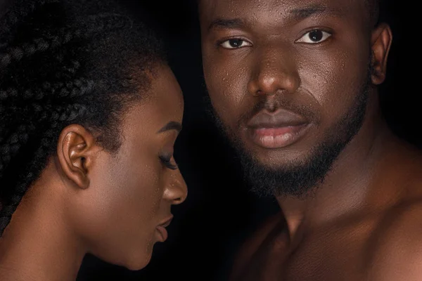 Belo jovem casal afro-americano com gotas de água em rostos posando isolado no preto — Fotografia de Stock