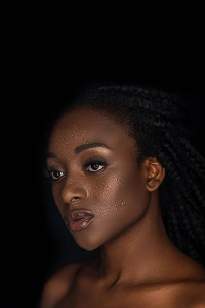 Belle sensuelle jeune femme afro-américaine avec des gouttes d'eau sur le visage regardant loin isolé sur noir — Photo de stock