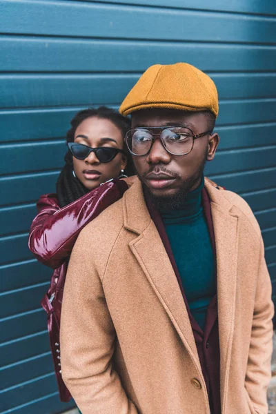 Moda joven africano americano pareja en chaqueta y abrigo posando juntos fuera - foto de stock