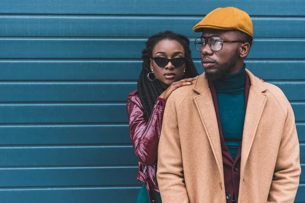 Beautiful stylish young african american couple in jacket and overcoat posing together outside — Stock Photo