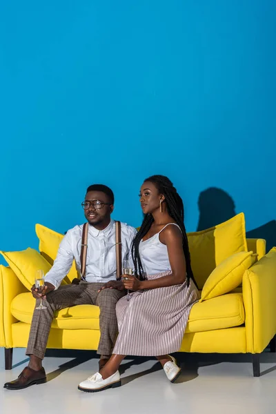 Stylish young african american couple drinking champagne while sitting on sofa — Stock Photo