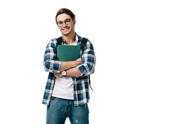 Sonriente guapo estudiante sosteniendo copybook y mirando cámara aislado en blanco - foto de stock