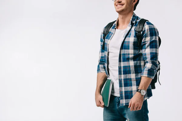 Обрезанное изображение улыбающегося студента, держащего тетрадь изолированной на белом — стоковое фото