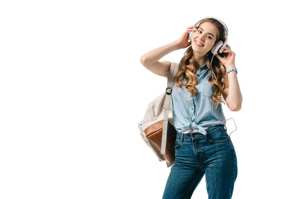 Sonriente hermosa estudiante escuchando música con auriculares aislados en blanco - foto de stock