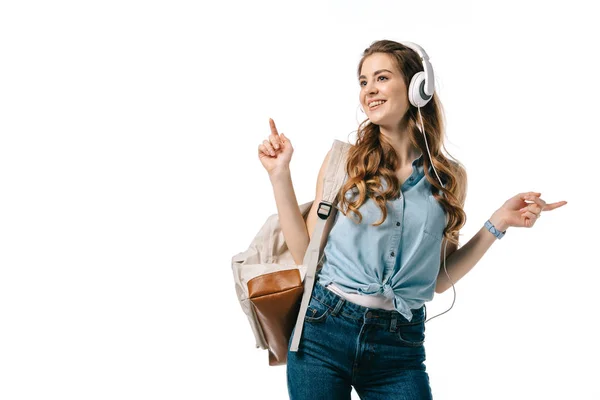 Hermosa estudiante escuchando música con auriculares y bailando aislado en blanco - foto de stock