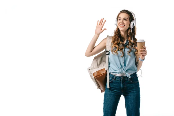 Lächelnde schöne Studentin winkt mit der Hand und hört isoliert auf weißem Grund Musik — Stockfoto