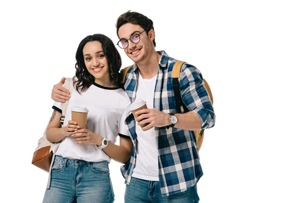 Estudiantes multiculturales abrazando y sosteniendo tazas de café desechables aislados en blanco - foto de stock