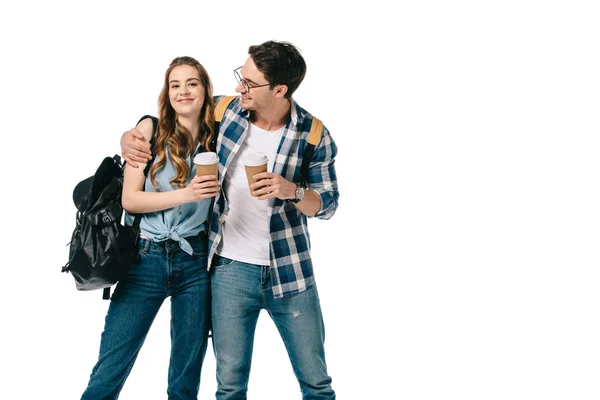 Jóvenes estudiantes abrazando y sosteniendo tazas de café desechables aislados en blanco - foto de stock