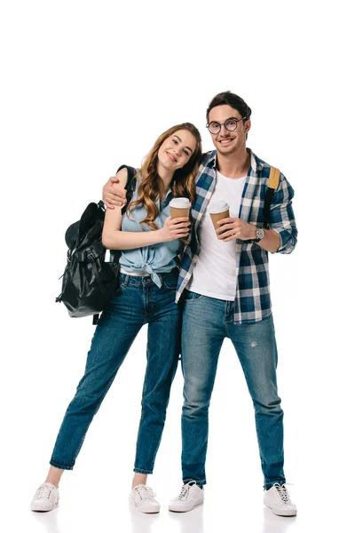 Jóvenes estudiantes abrazando y sosteniendo tazas de café desechables aislados en blanco - foto de stock