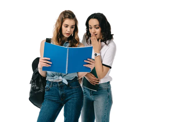 Estudiantes multiculturales sorprendidos mirando copybook aislado en blanco - foto de stock