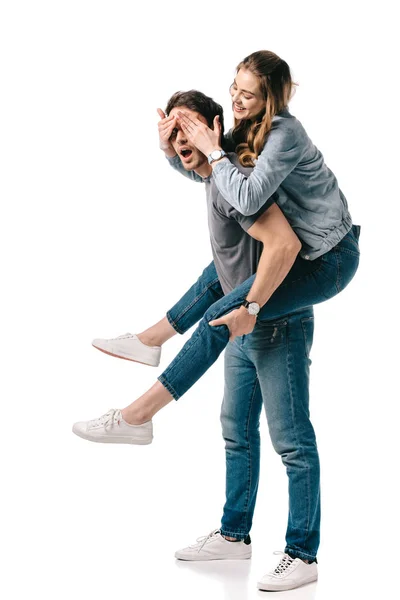 Boyfriend giving piggyback to girlfriend and she covering eyes isolated on white — Stock Photo