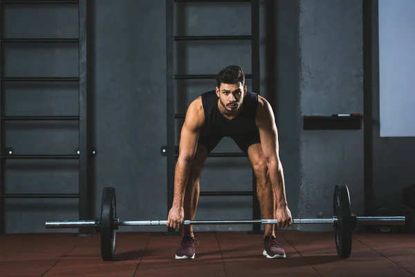 Vista frontal do jovem desportista se preparando para levantar barbell no salão de esportes — Fotografia de Stock