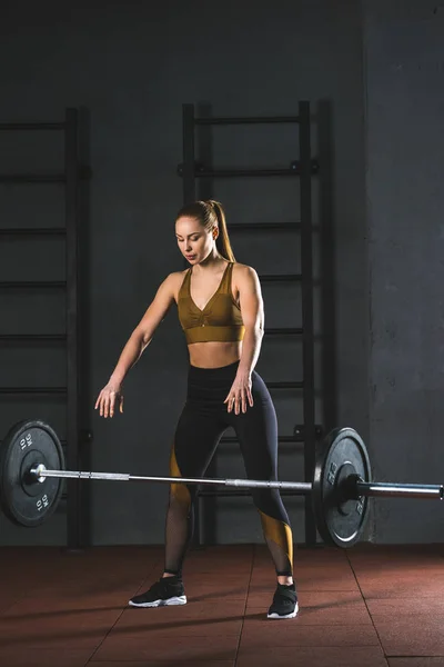 Young caucasian sportswoman letting go barbell  in sports hall — Stock Photo