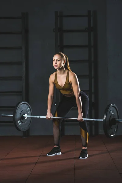 Вид спереди на юную спортсменку, занимающуюся с штангой в спортзале — стоковое фото