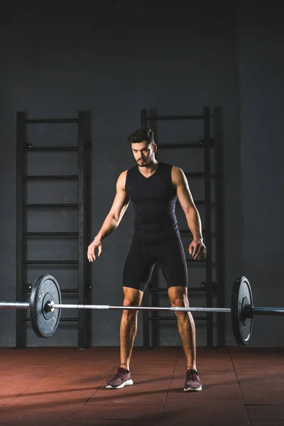 Jovem esportista caucasiano soltando barbell no salão de esportes — Fotografia de Stock