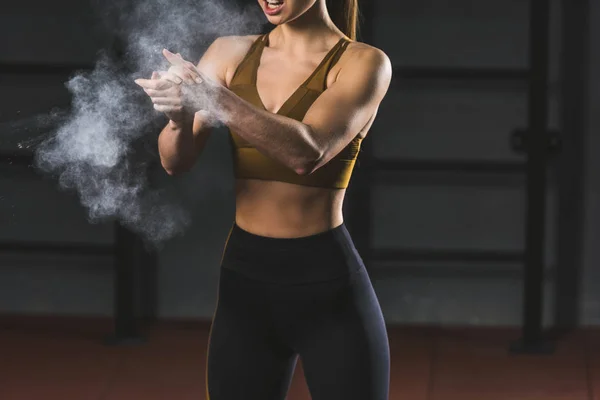 Обрізане зображення молодої спортсменки, що розкладає крейдяний порошок в руках для занять спортом у спортивному залі — стокове фото