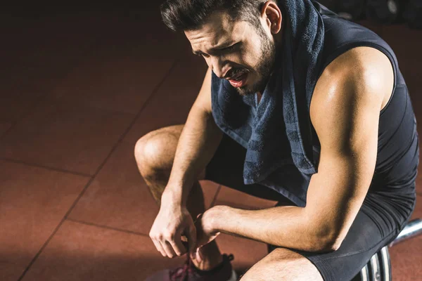 High angle view of upset young sportsman sitting on barbell in gym — Stock Photo