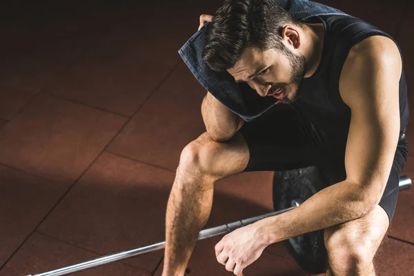 Vue grand angle de l'athlète fatigué essuyant visage par serviette dans la salle de gym — Photo de stock