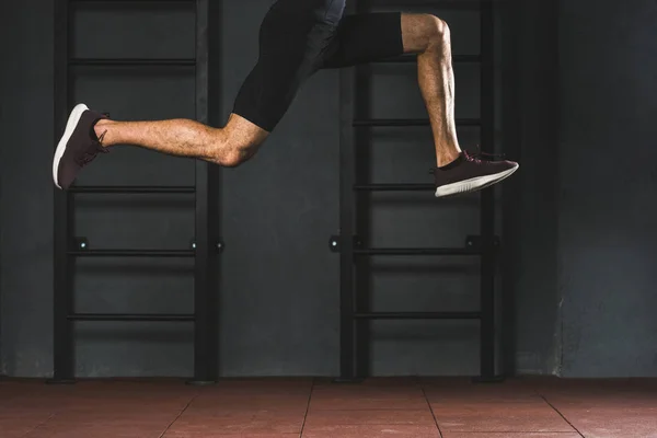 Imagen recortada de saltando deportista haciendo ejercicio cardiovascular en el gimnasio - foto de stock