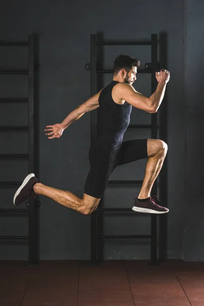 Vista laterale del giovane sportivo di salto in palestra — Foto stock