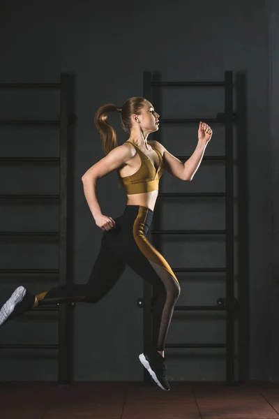 Vue latérale de la jeune sportive sauteuse dans la salle de gym — Photo de stock