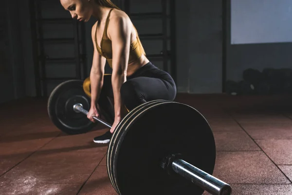 Cropped image de la jeune sportive se préparer à soulever haltère dans la salle de gym — Photo de stock